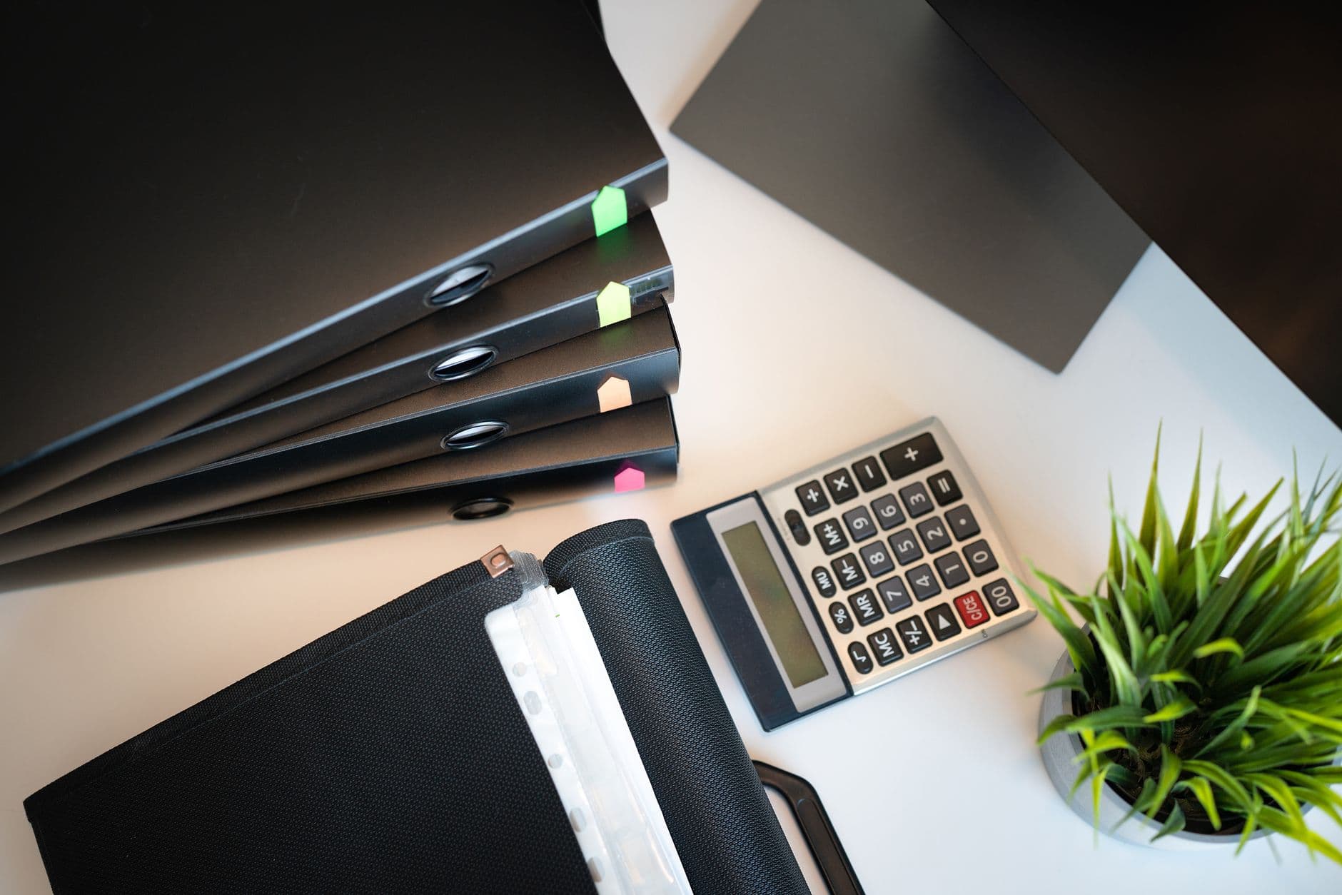 Top view of a tidy office desk with files, a calculator, and a plant.