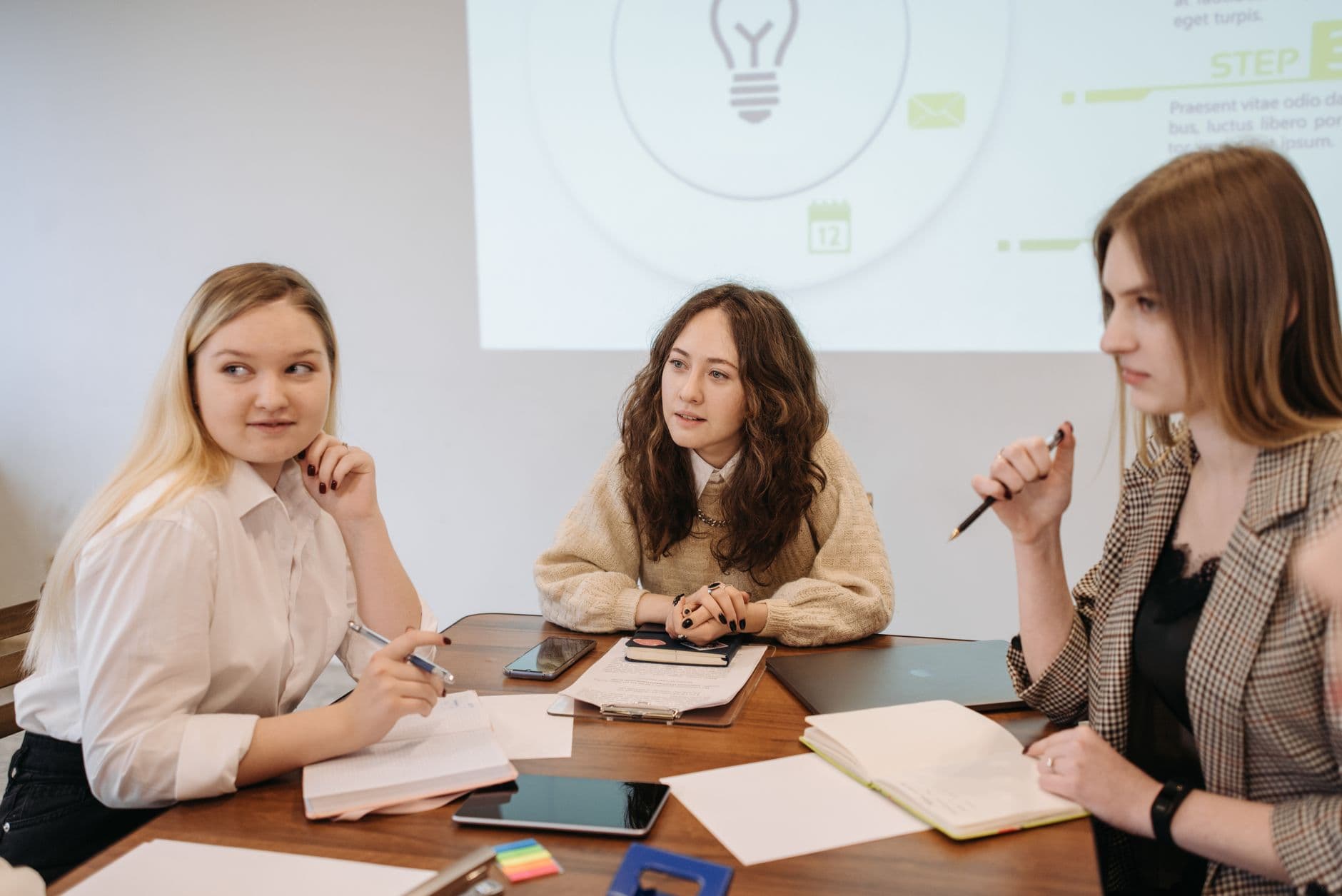Three young women engaged in a brainstorming session, sharing ideas and notes.