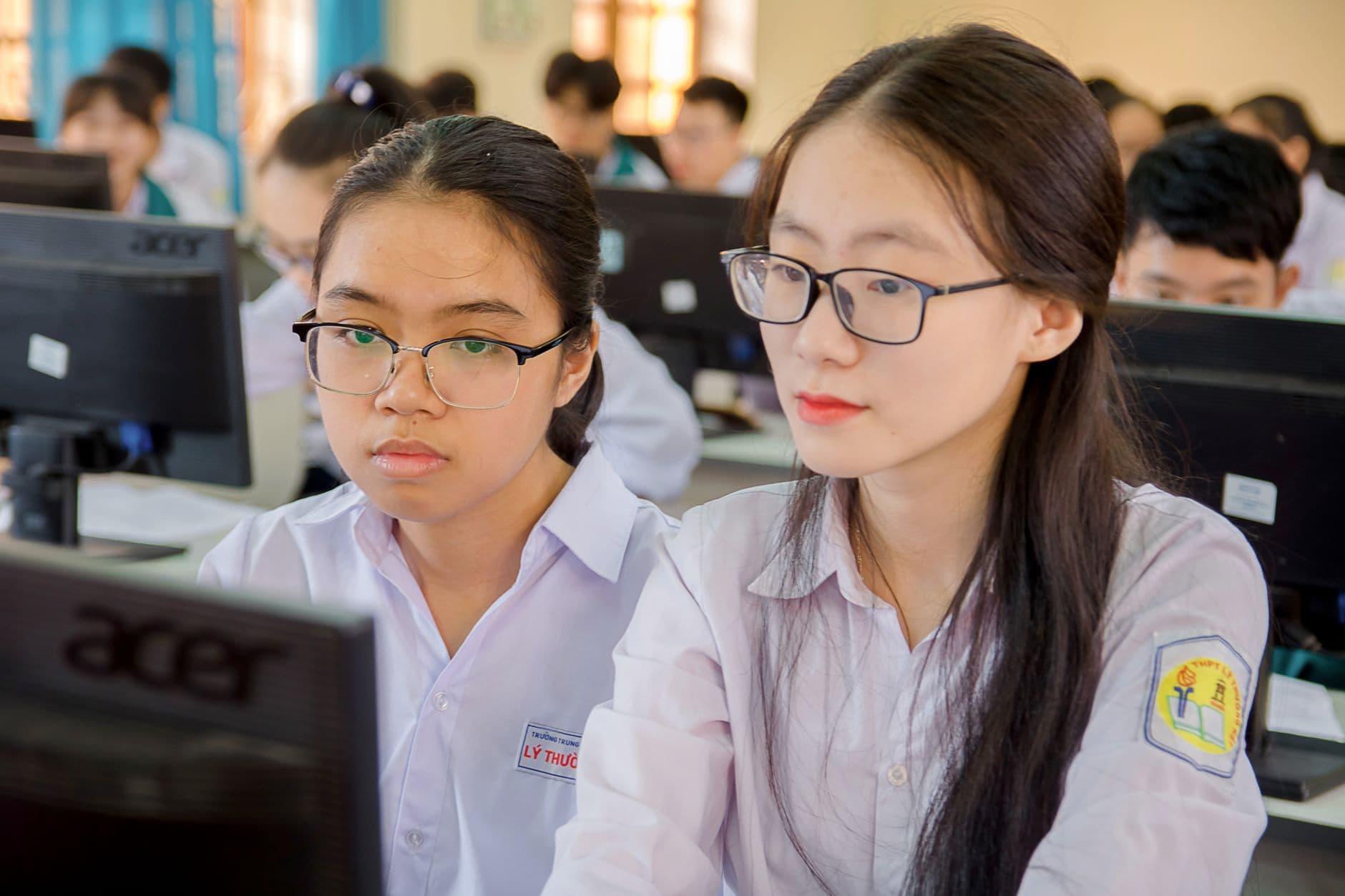 Two students working at computers in a university classroom.