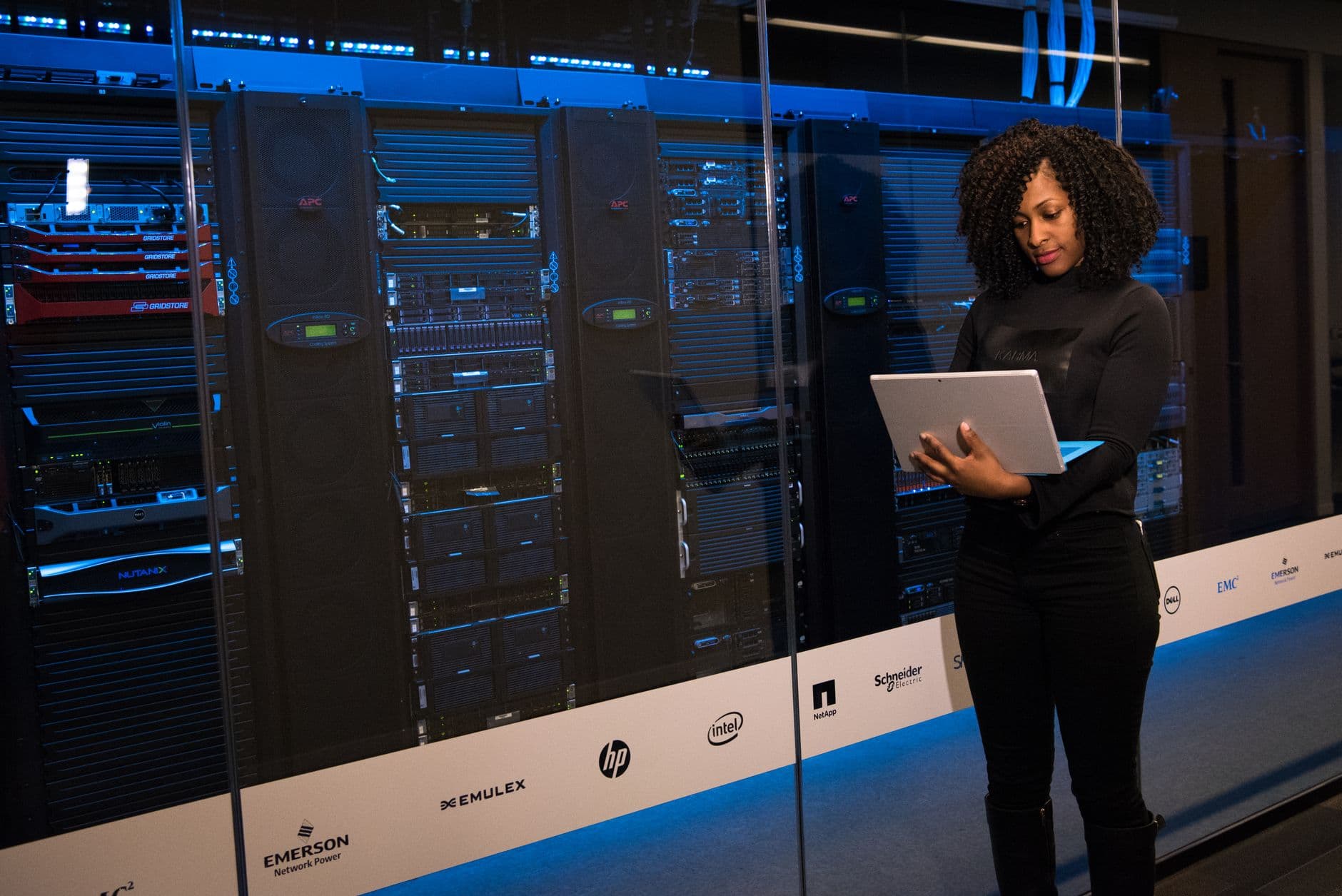 An engineer working at a laptop beside data servers.