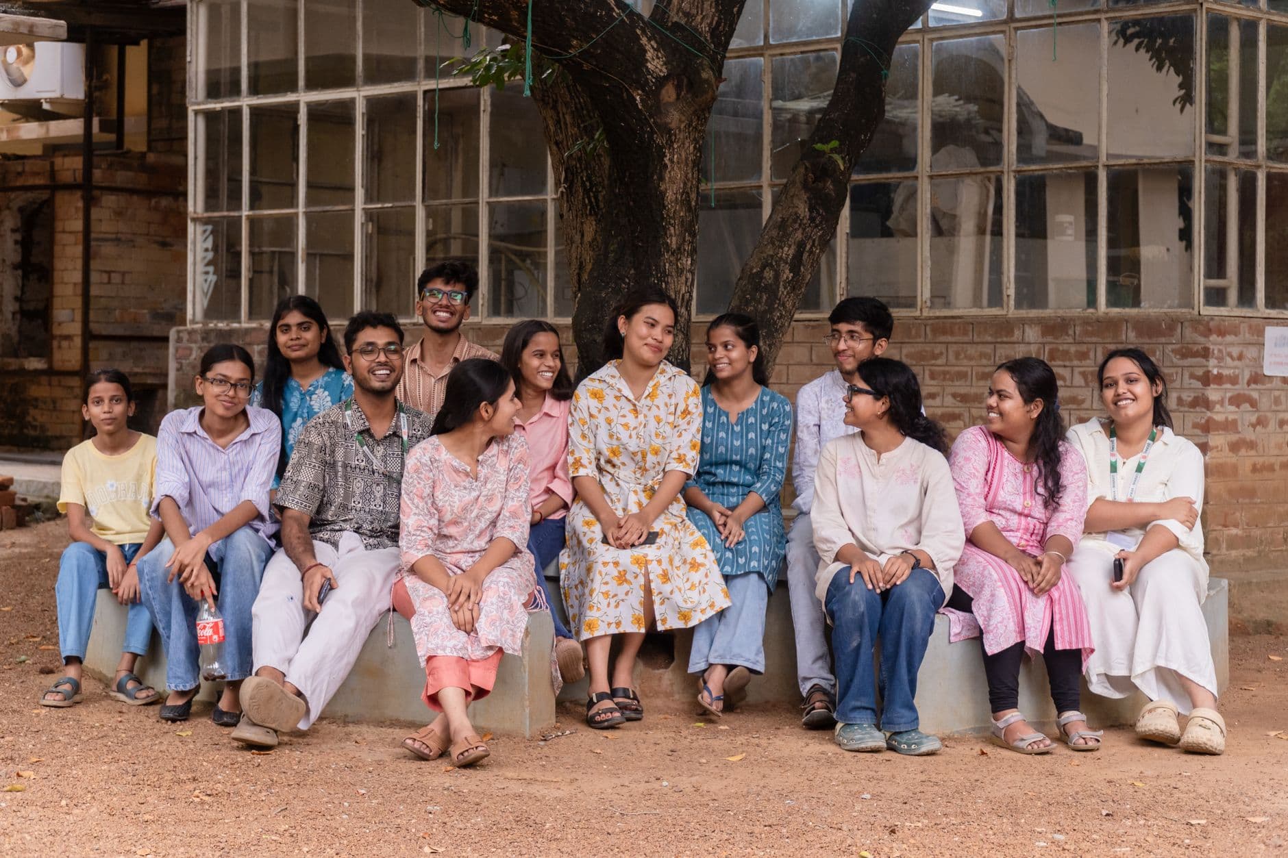 Students sitting together under a tree on an Indian college campus.
