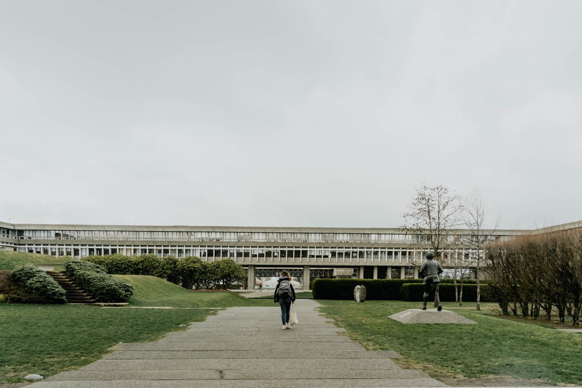 Woman walking towards the main building at Simon Fraser University in Burnaby, BC, Canada.