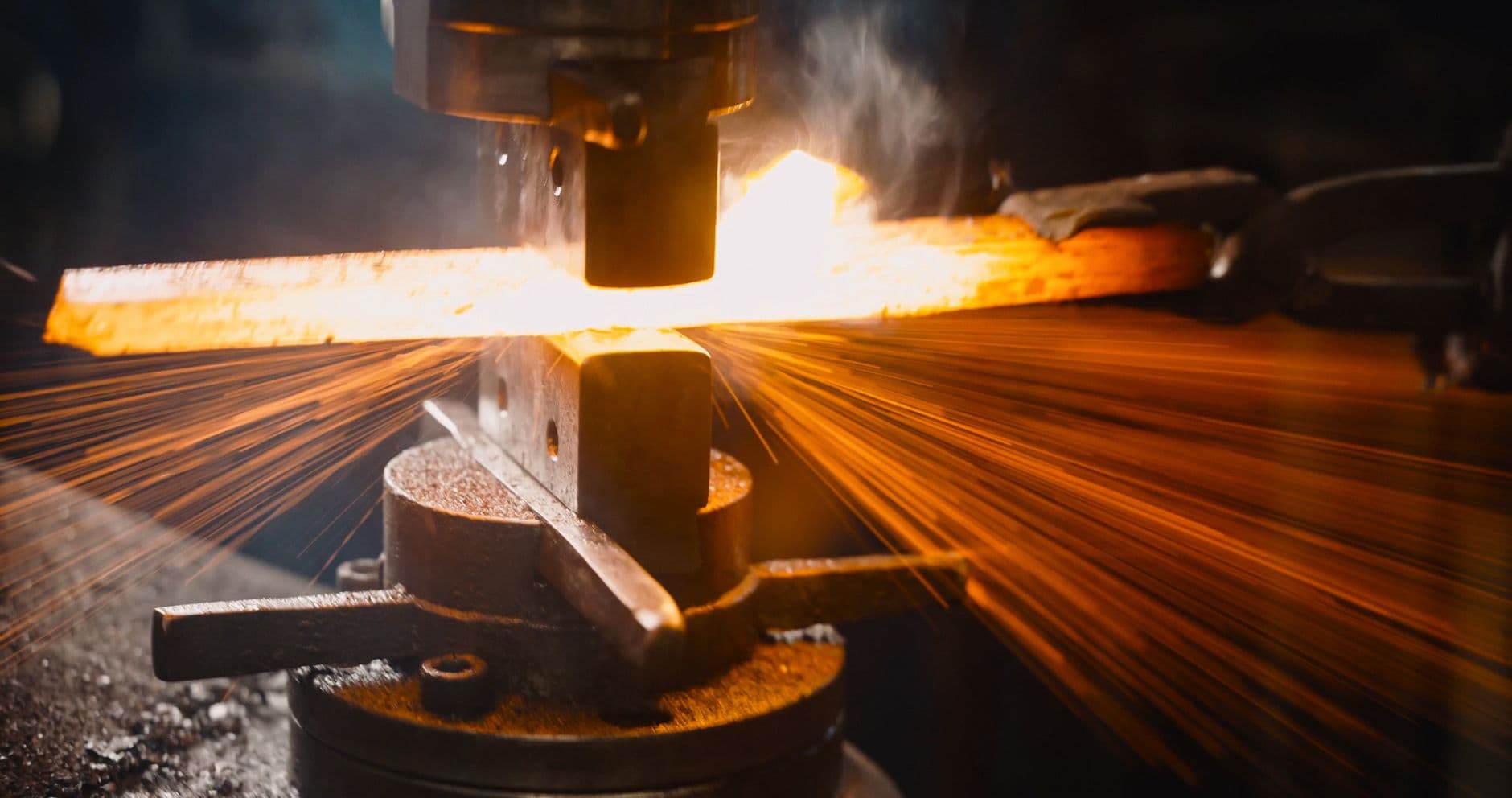Intense image showcasing sparks from metal forging at a foundry with vibrant lighting effects.