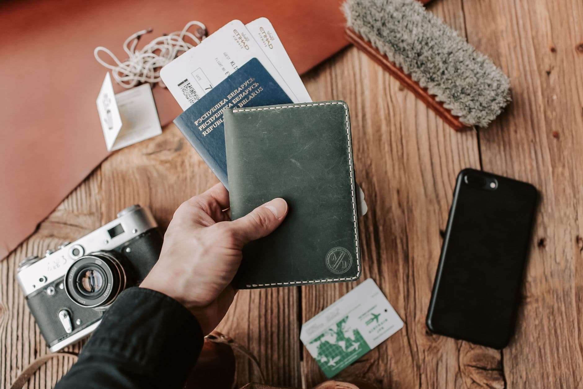 A hand holding a passport alongside travel documents.