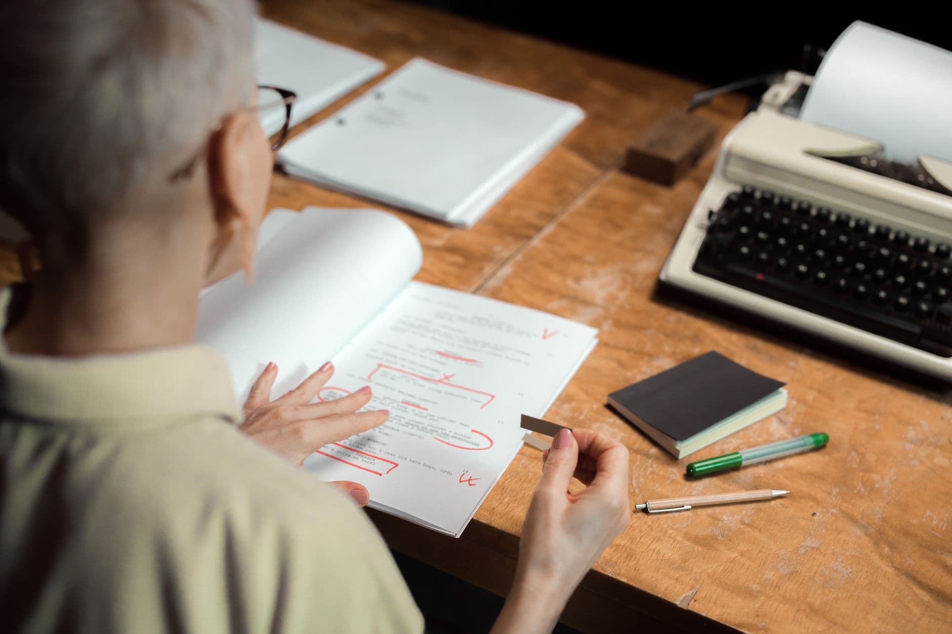 A printed page being marked up with a red pen at a desk.