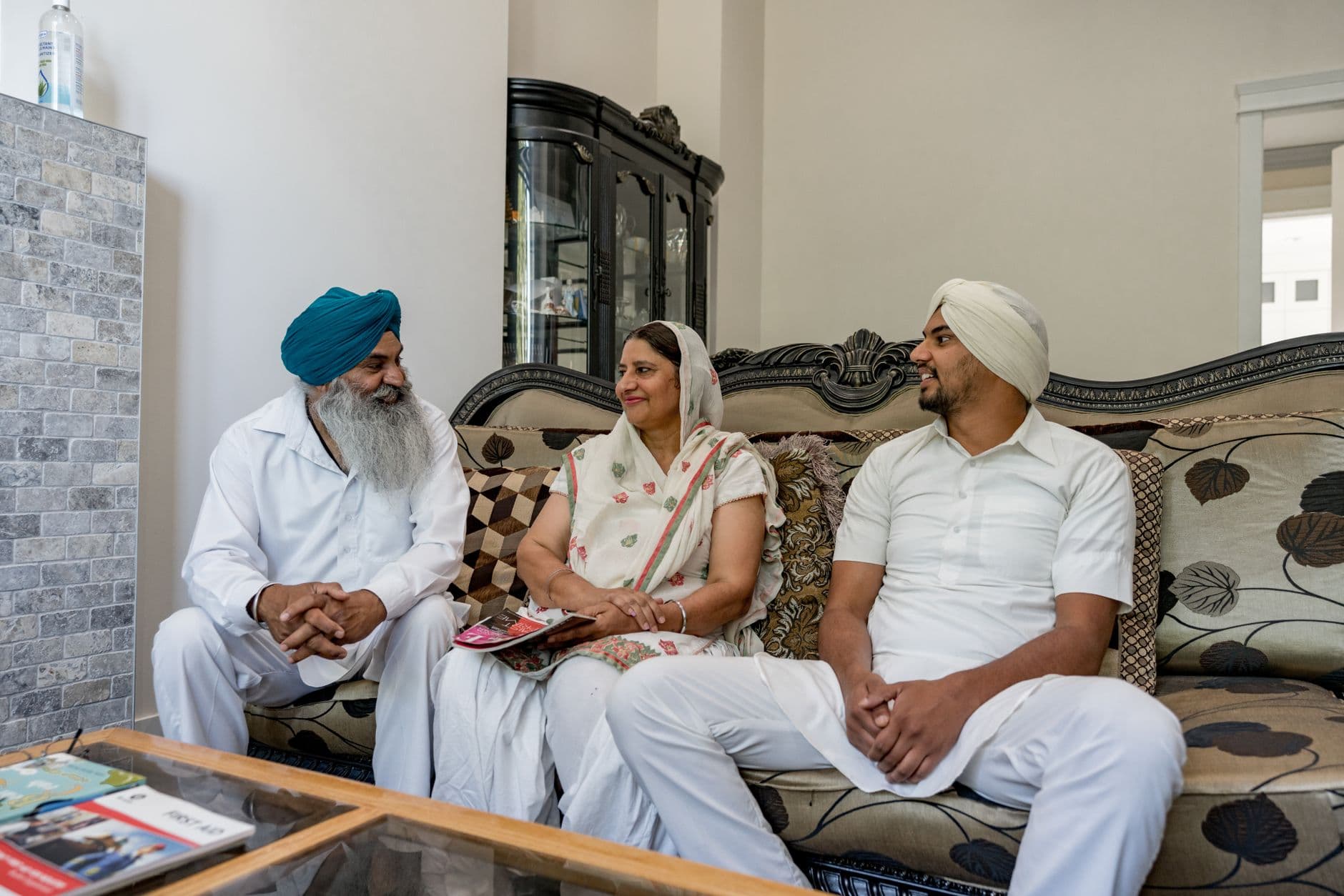 A family of three sitting together on a sofa at home.