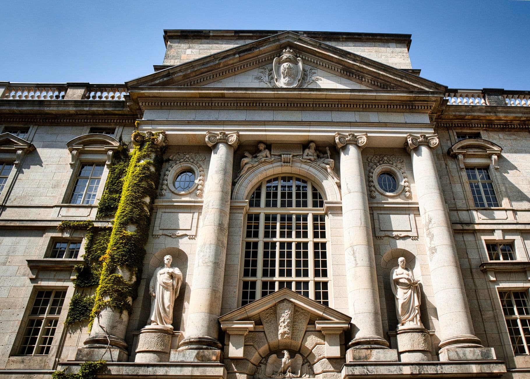 Statues adorn the neoclassical facade of Humboldt University in Berlin, Germany.