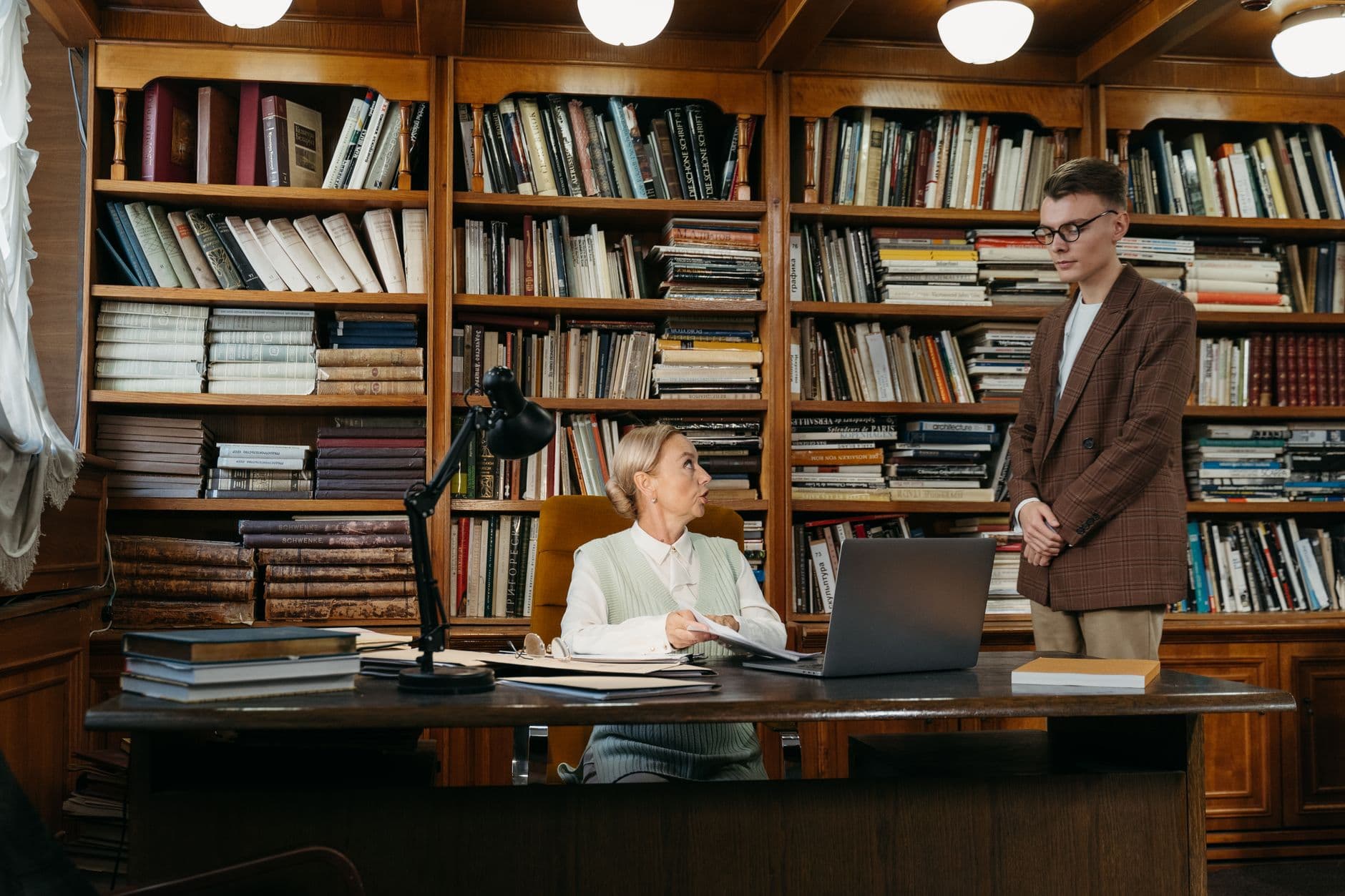 Two people talking between library shelves.