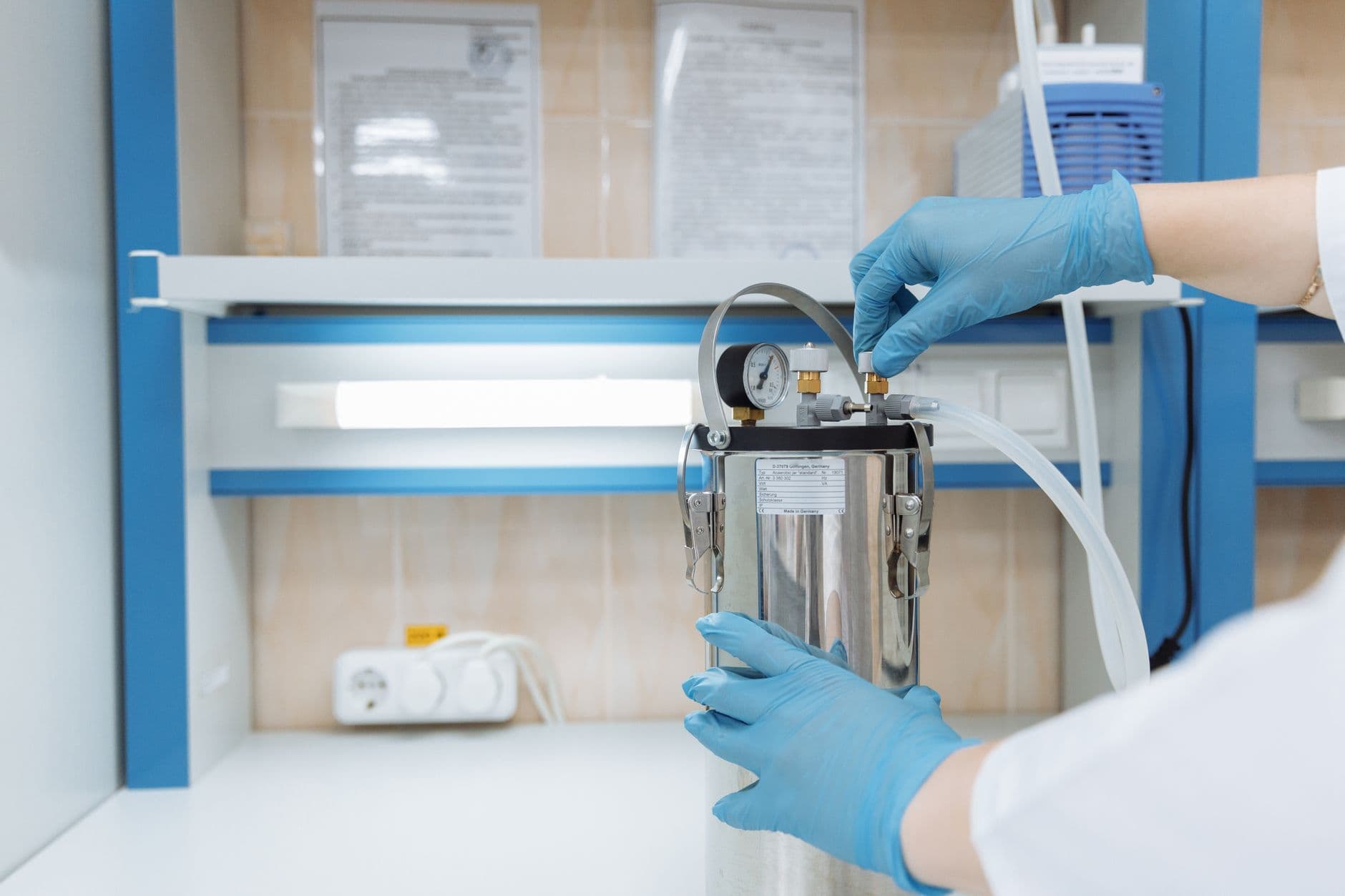 Scientist adjusting laboratory equipment with precision in a modern lab setting, wearing blue gloves.
