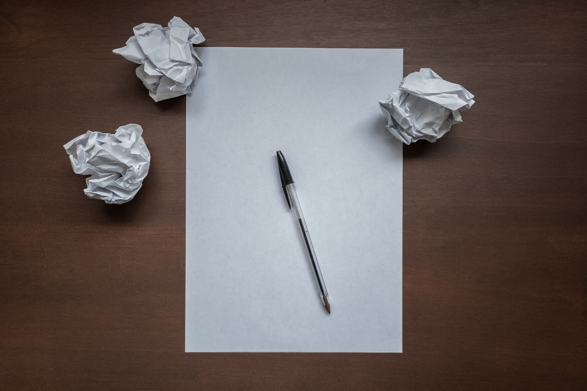 Crumpled paper and a pen on a desk.