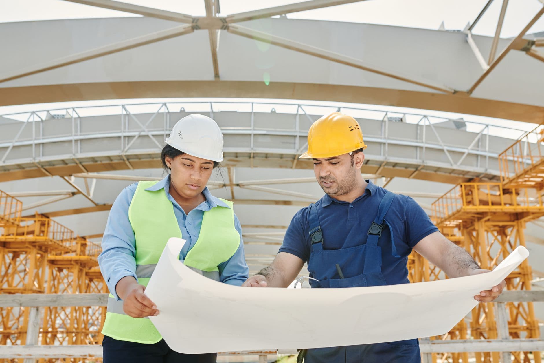 Two engineers reviewing drawings on a construction site.