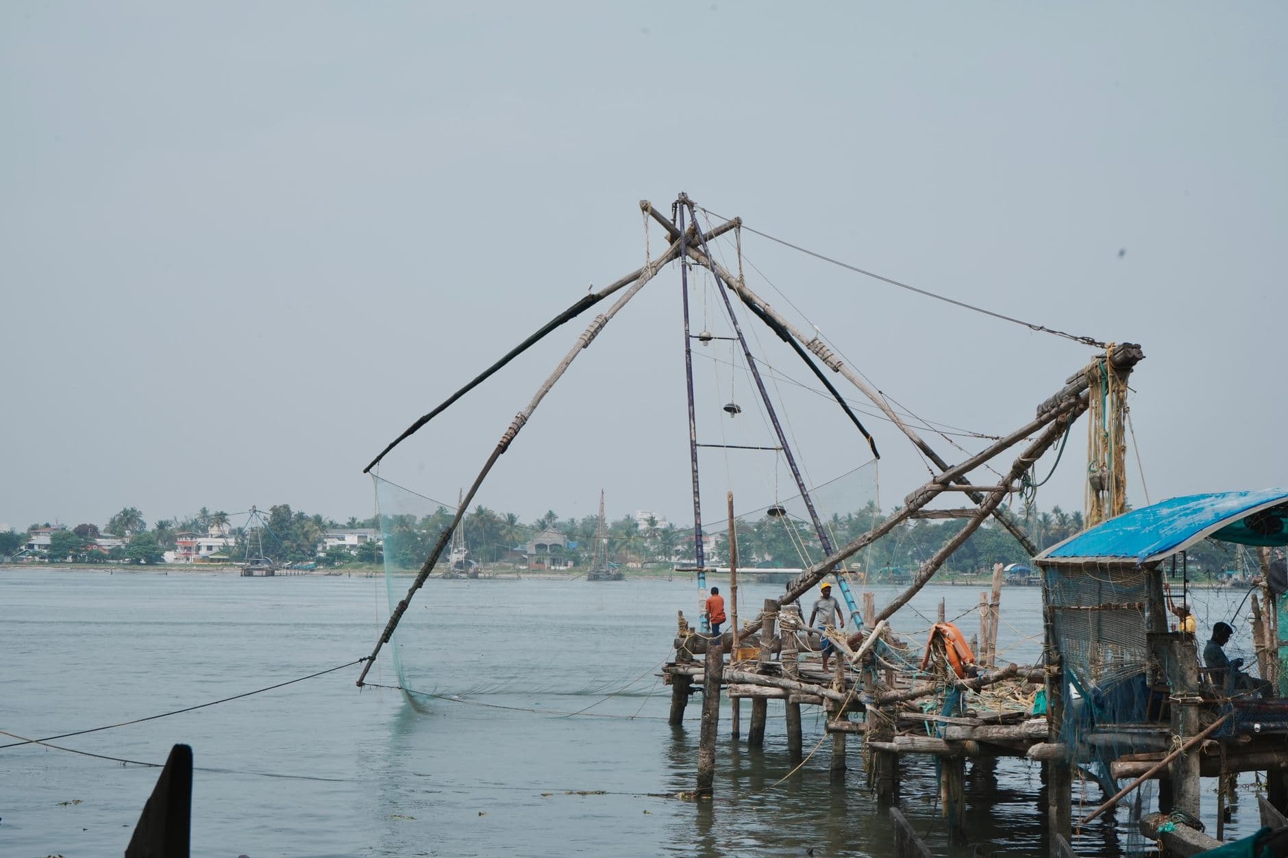 Scenic view of Chinese fishing nets in Kochi, Kerala with fishermen working on the shore.